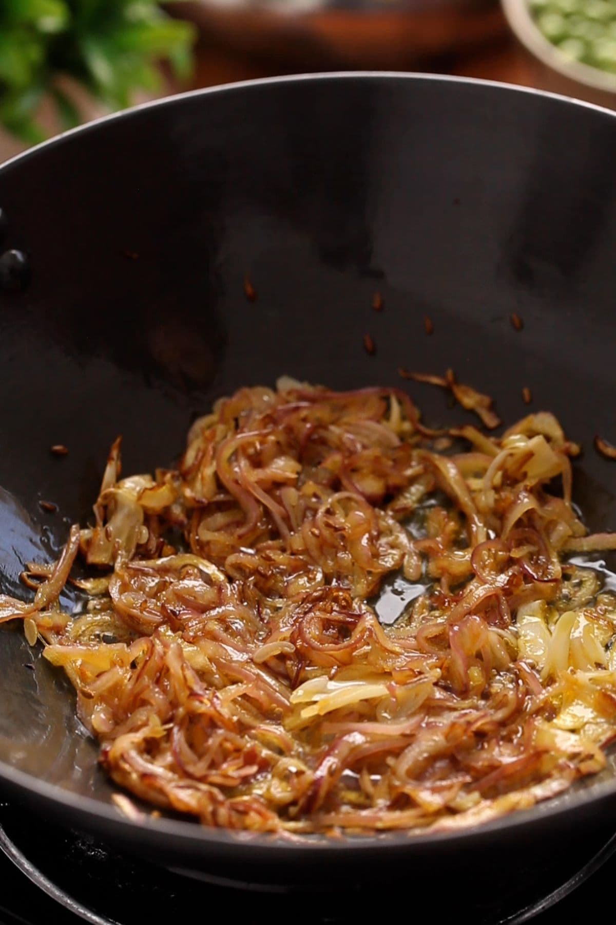 Golden fried onions in a black indian wok.