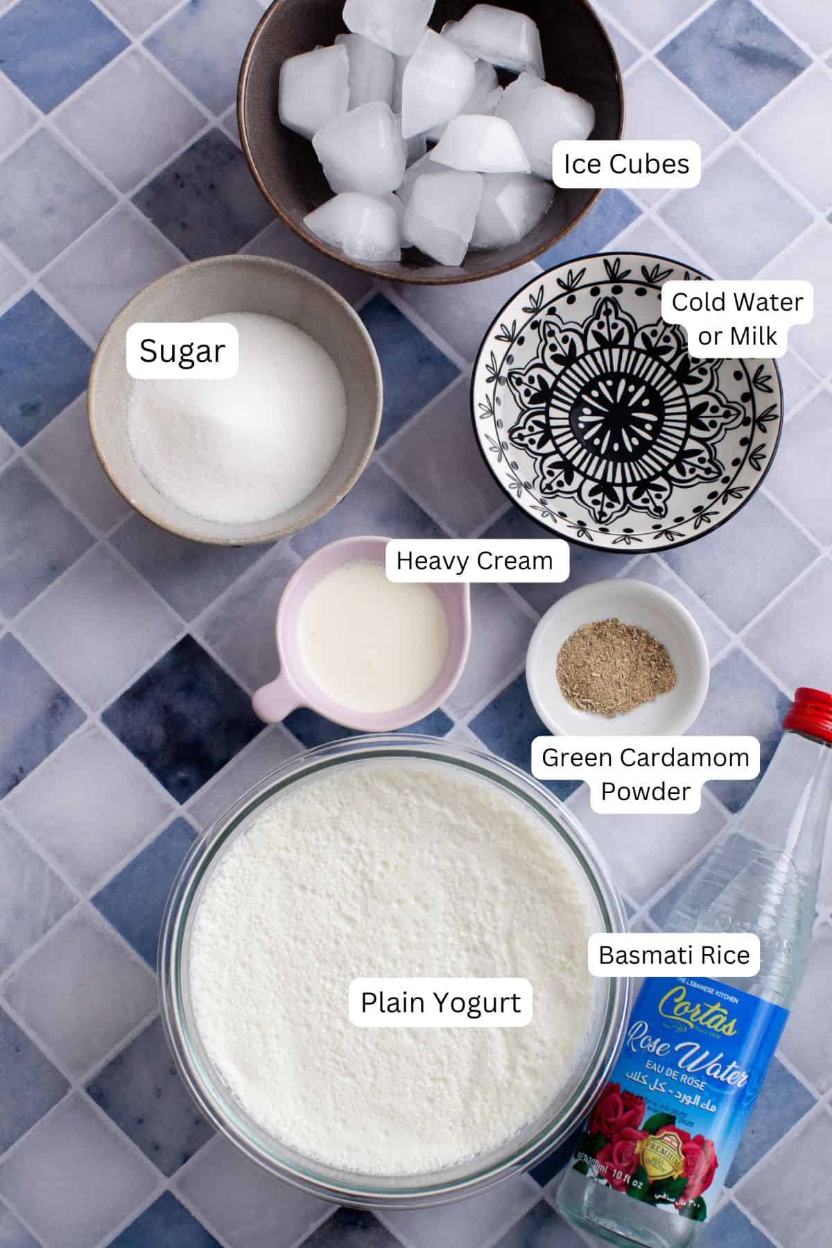 Ingredients needed to make sweet lassi placed on a blue & white tiled background.