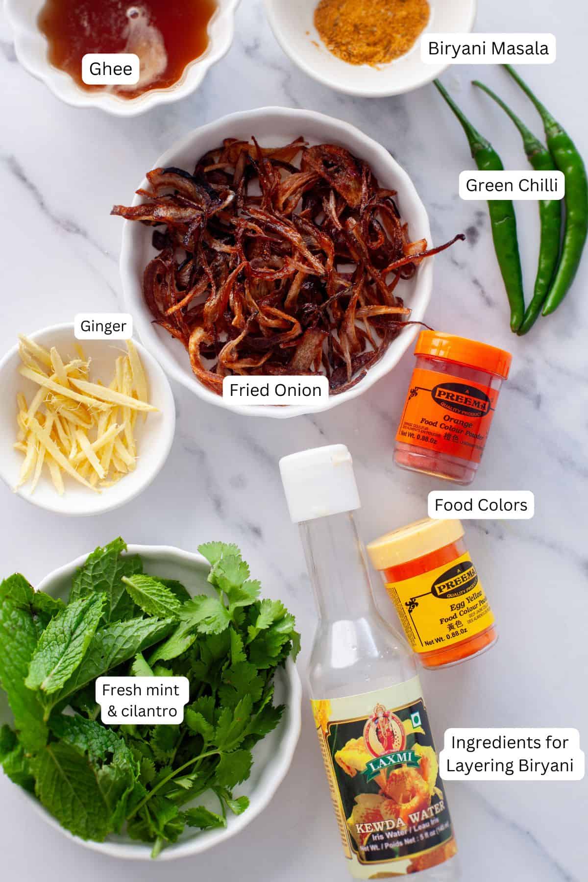 Ingredients needed to layer anda biryani placed on a white marble board.