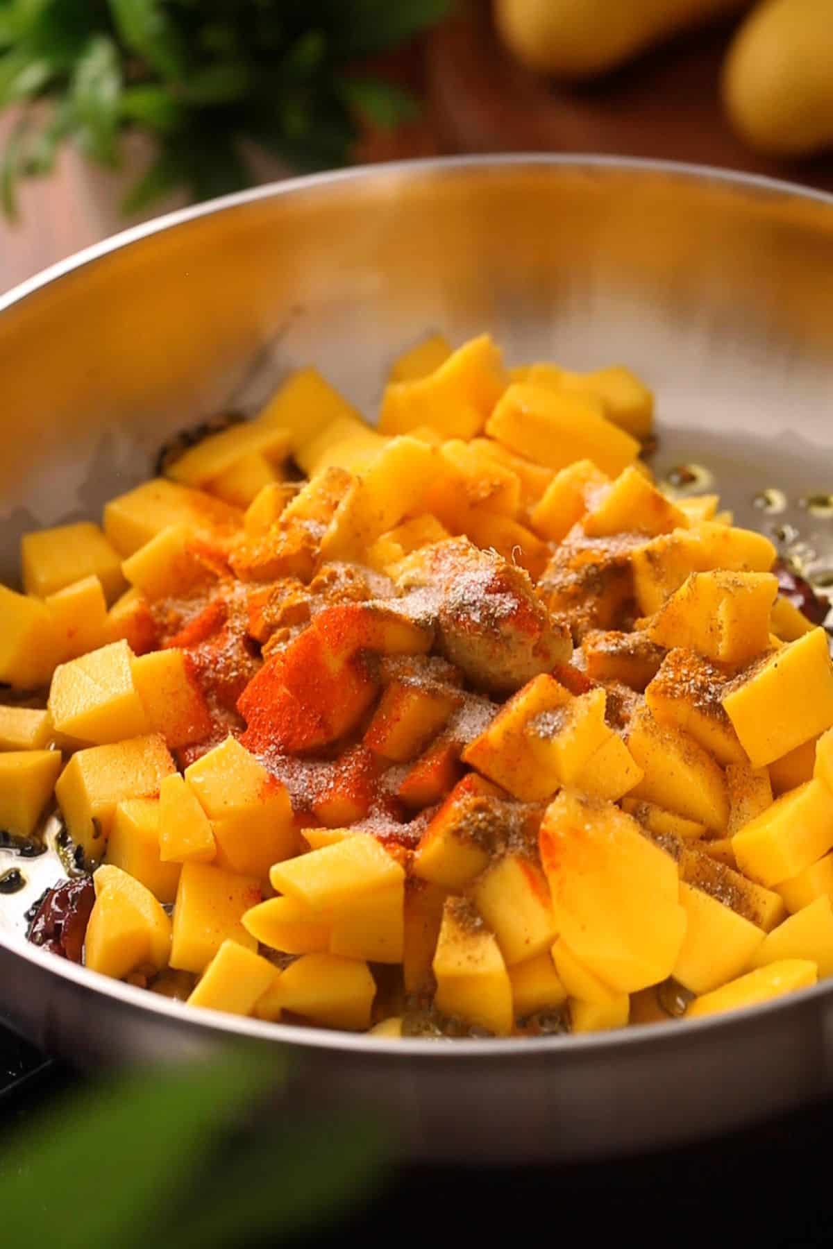 Diced mango, salt and ground spices are added to the pan.