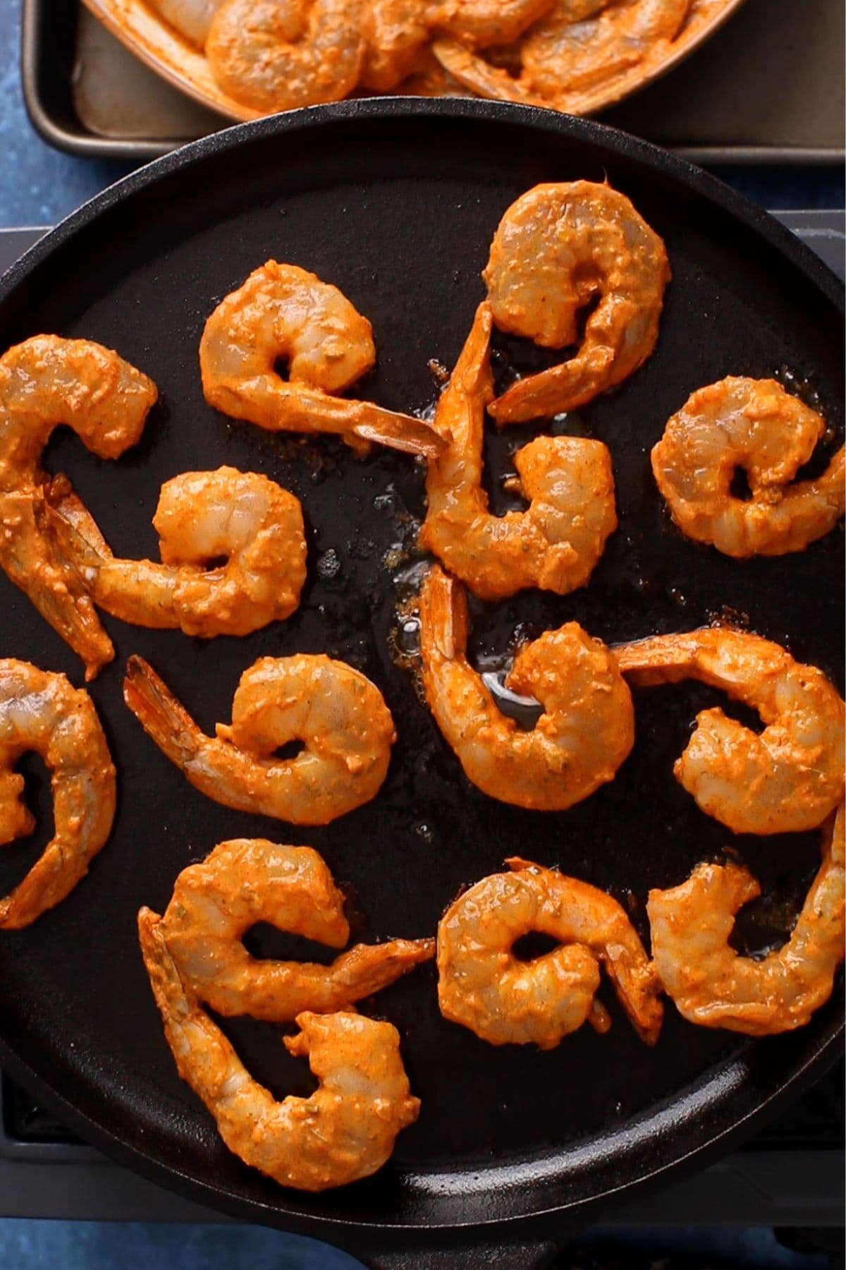 Marinated shrimps place in a cast iron pan.
