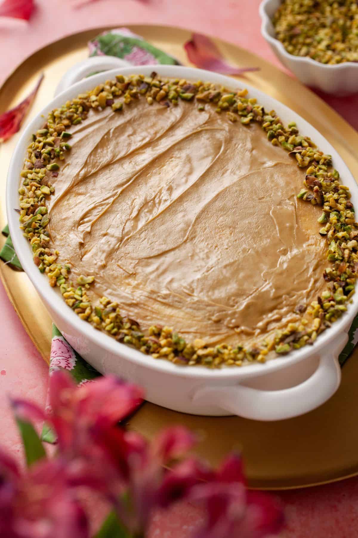 Side view of pistachio cardamom tiramisu in a white dish.