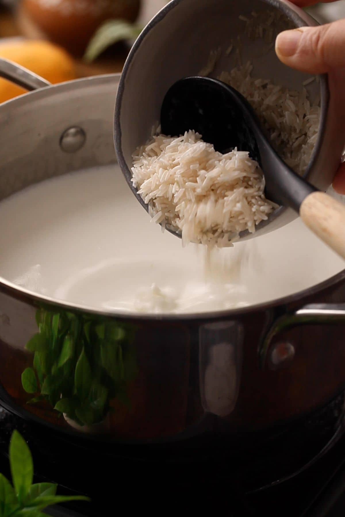 Soaked basmati rice is added to milk in a black pot.