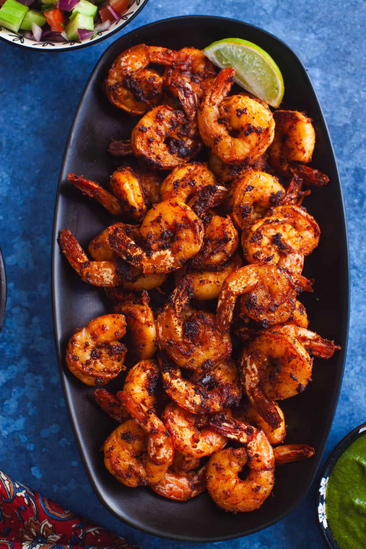 Tandoori shrimp tikka served on a black oval platter.