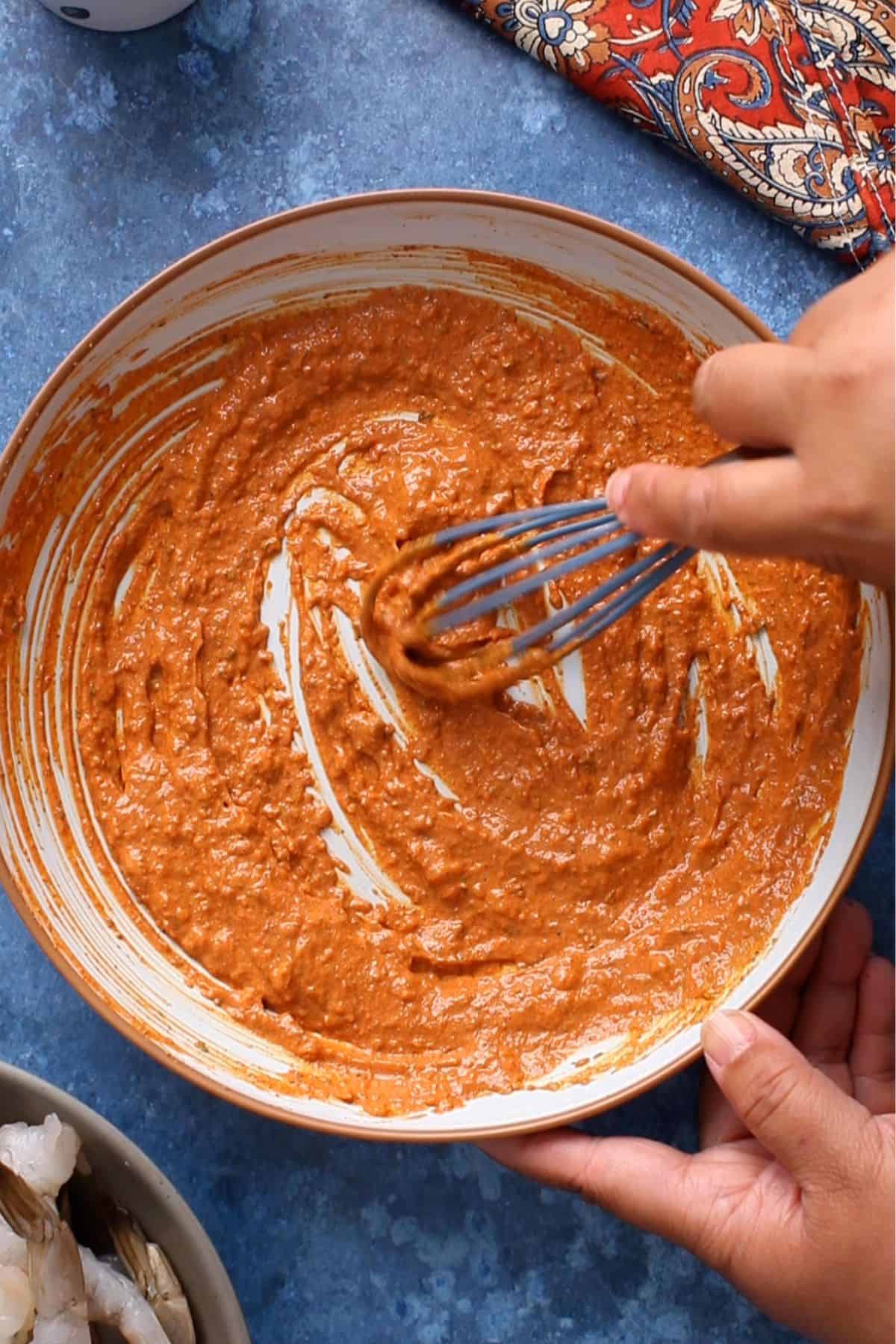 Mixing tandoori marinade using a blue whisk.