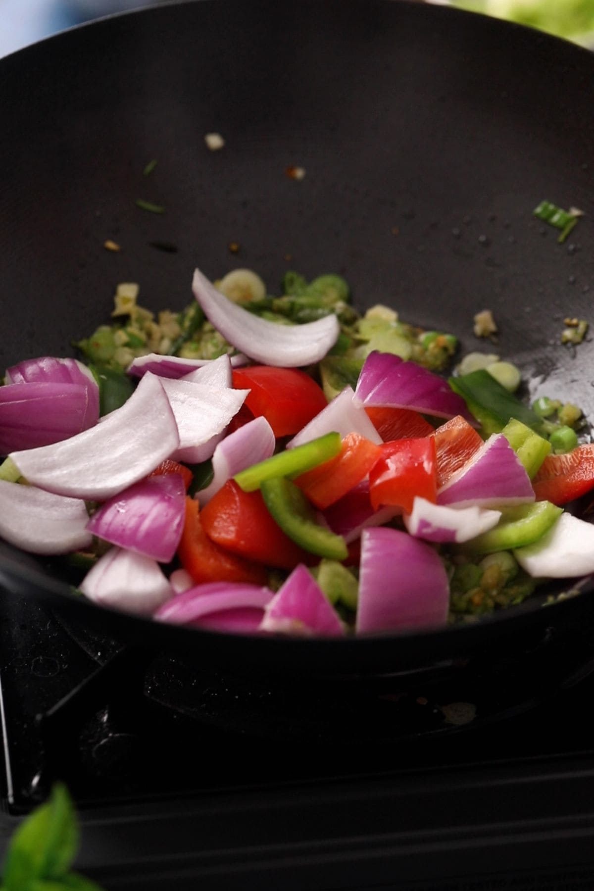 Onion and bell pepper chunks are added to the wok.