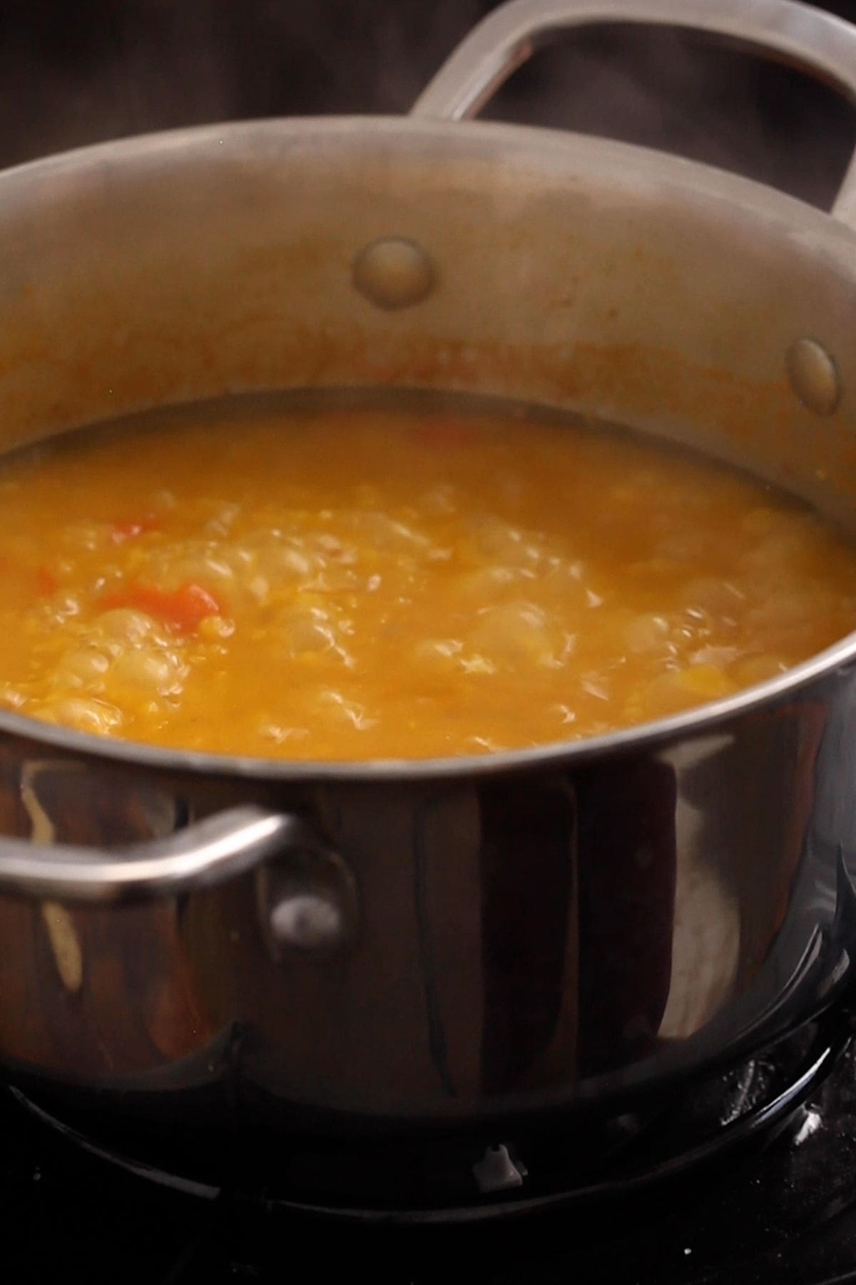 Dal in slow cooking in a stainless steel pot.