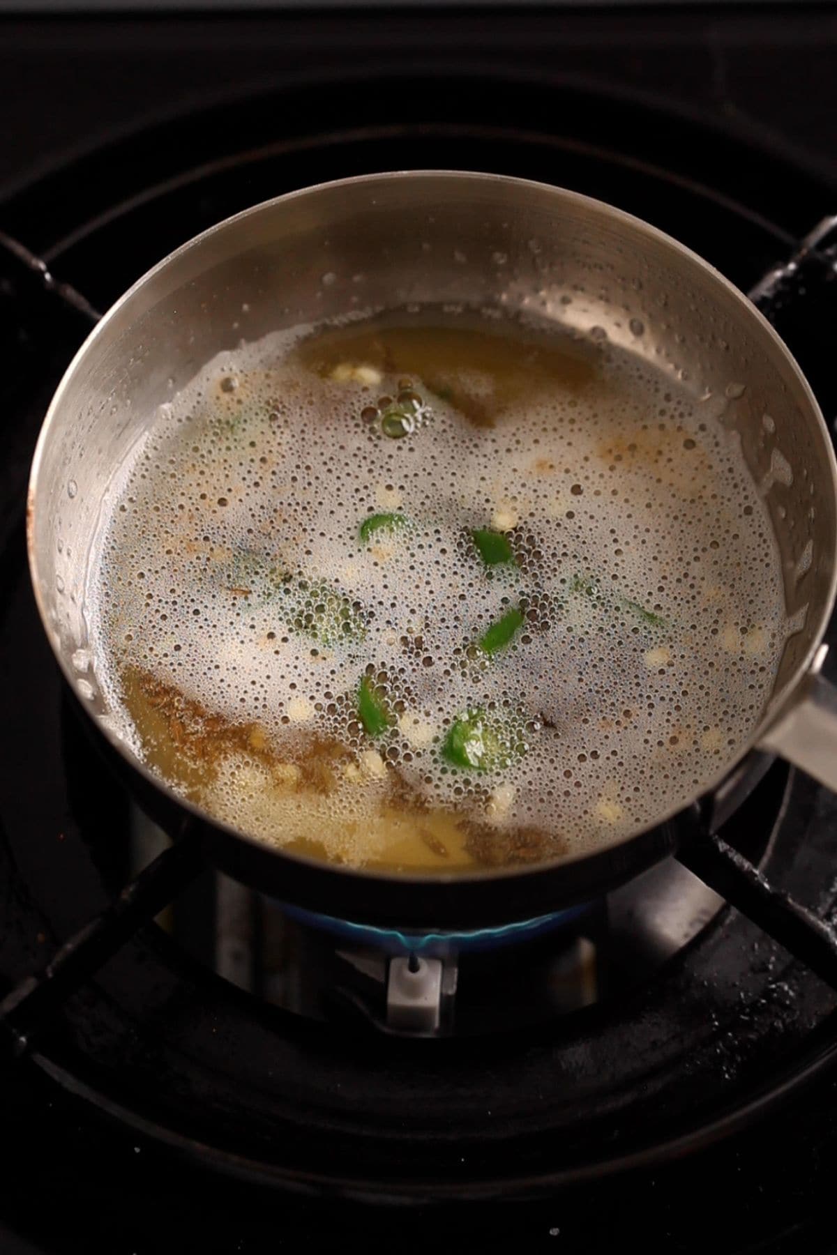 Tadka for dal is prepared in a small stainless steel pan.