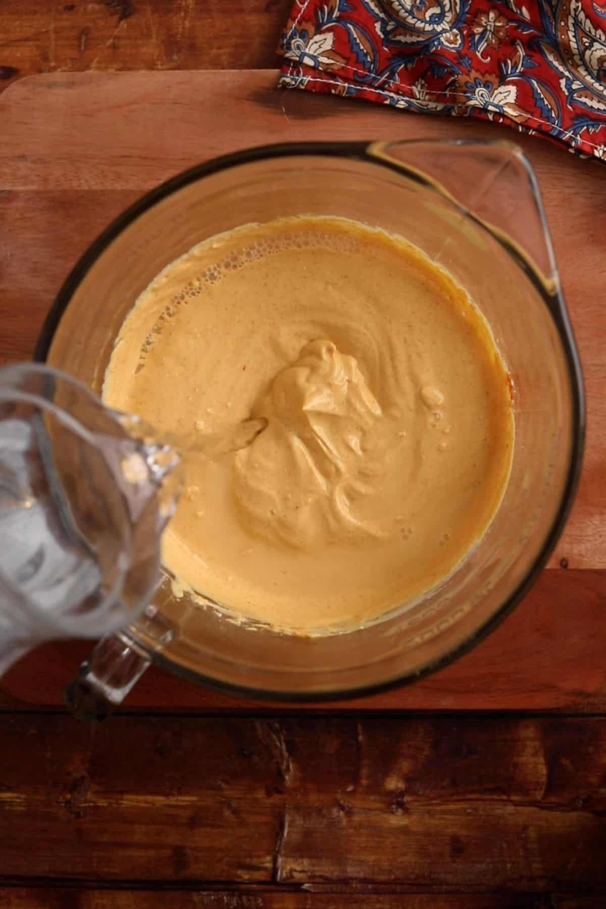 Water is added to whisked dahi and besan.