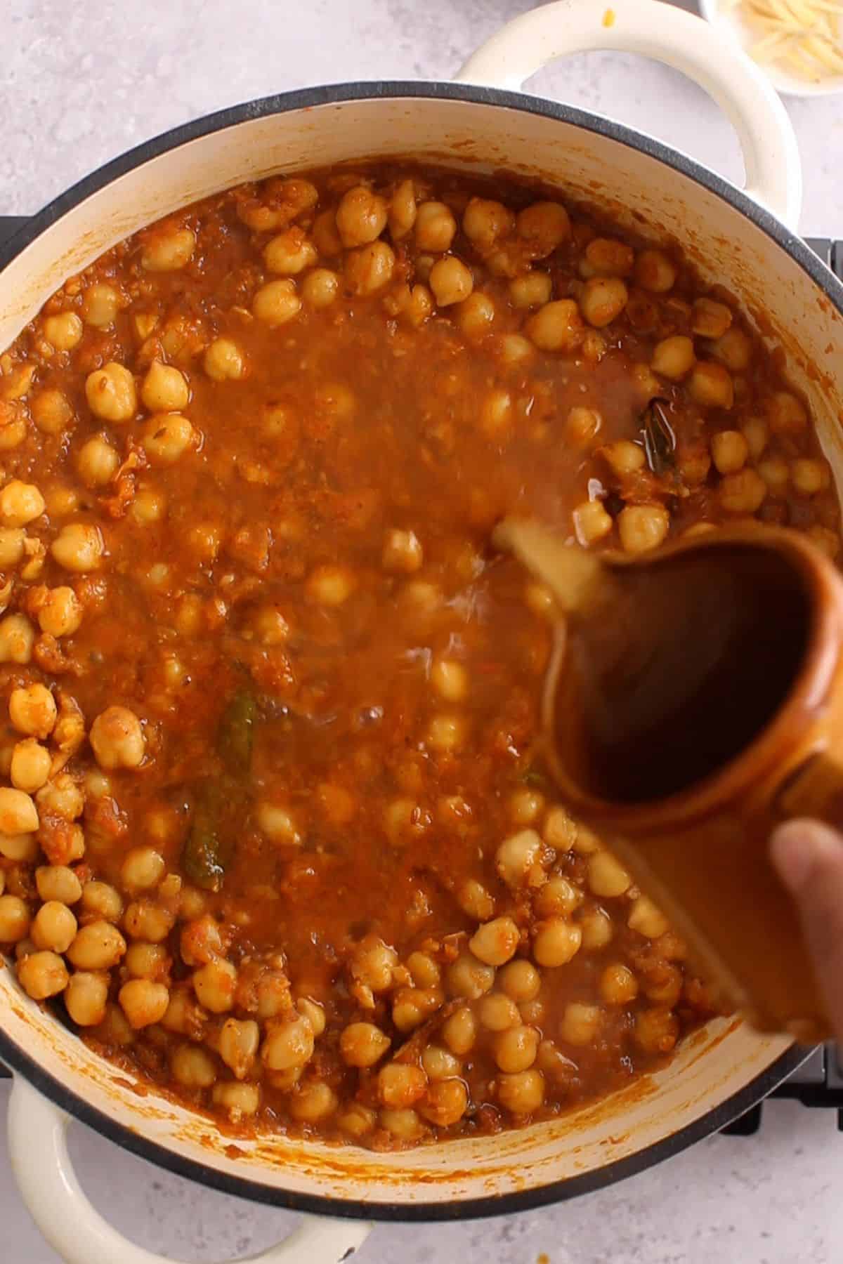 Chickpea stock is added to the curry.