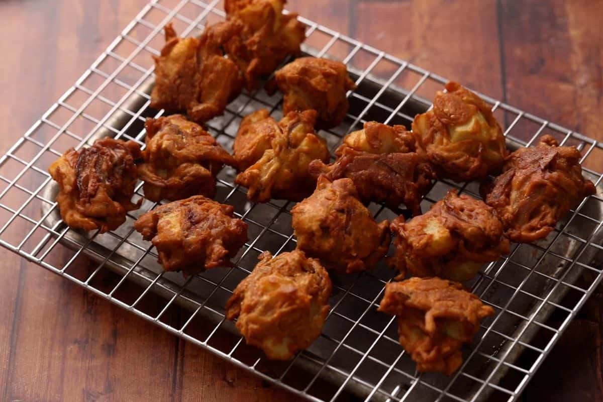Deep fried pakoras placed on a wire rack. 