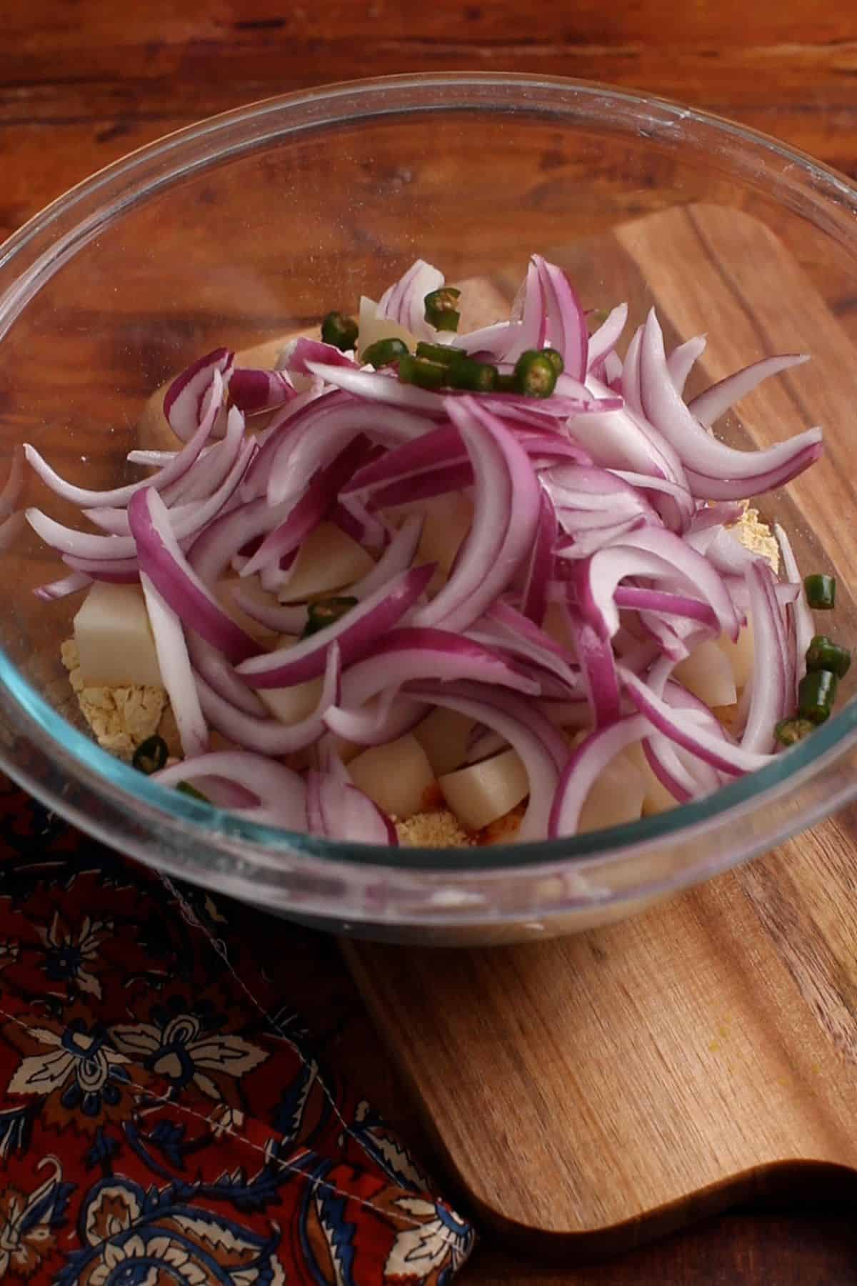 Onions, potatoes and green chillies are added. 