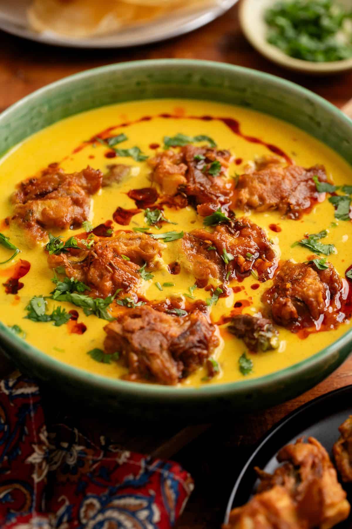 Side view of kadhi pakoda with papads in background.