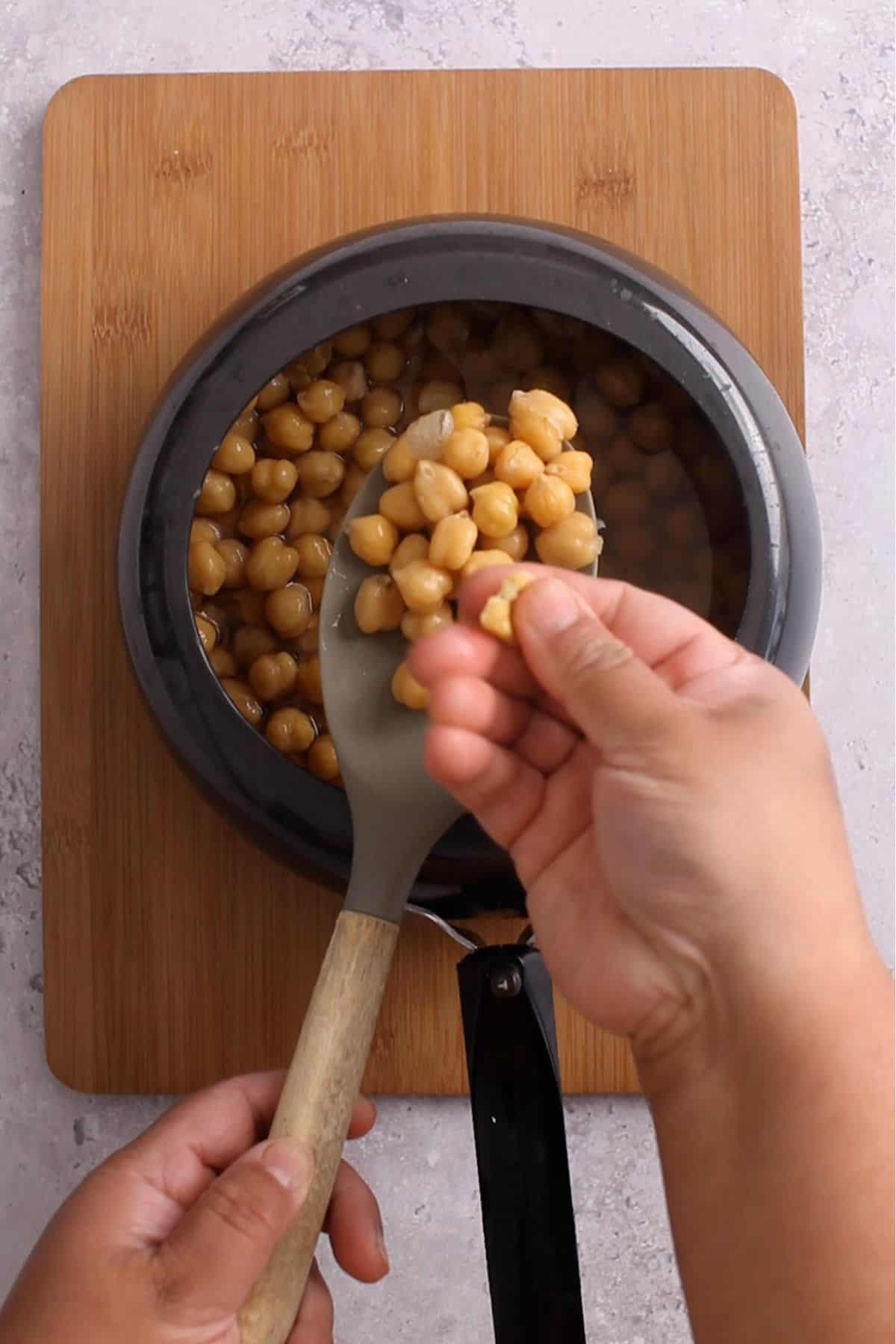 Checking the texture of boiled chickpeas by pressing them between finger and thumb.