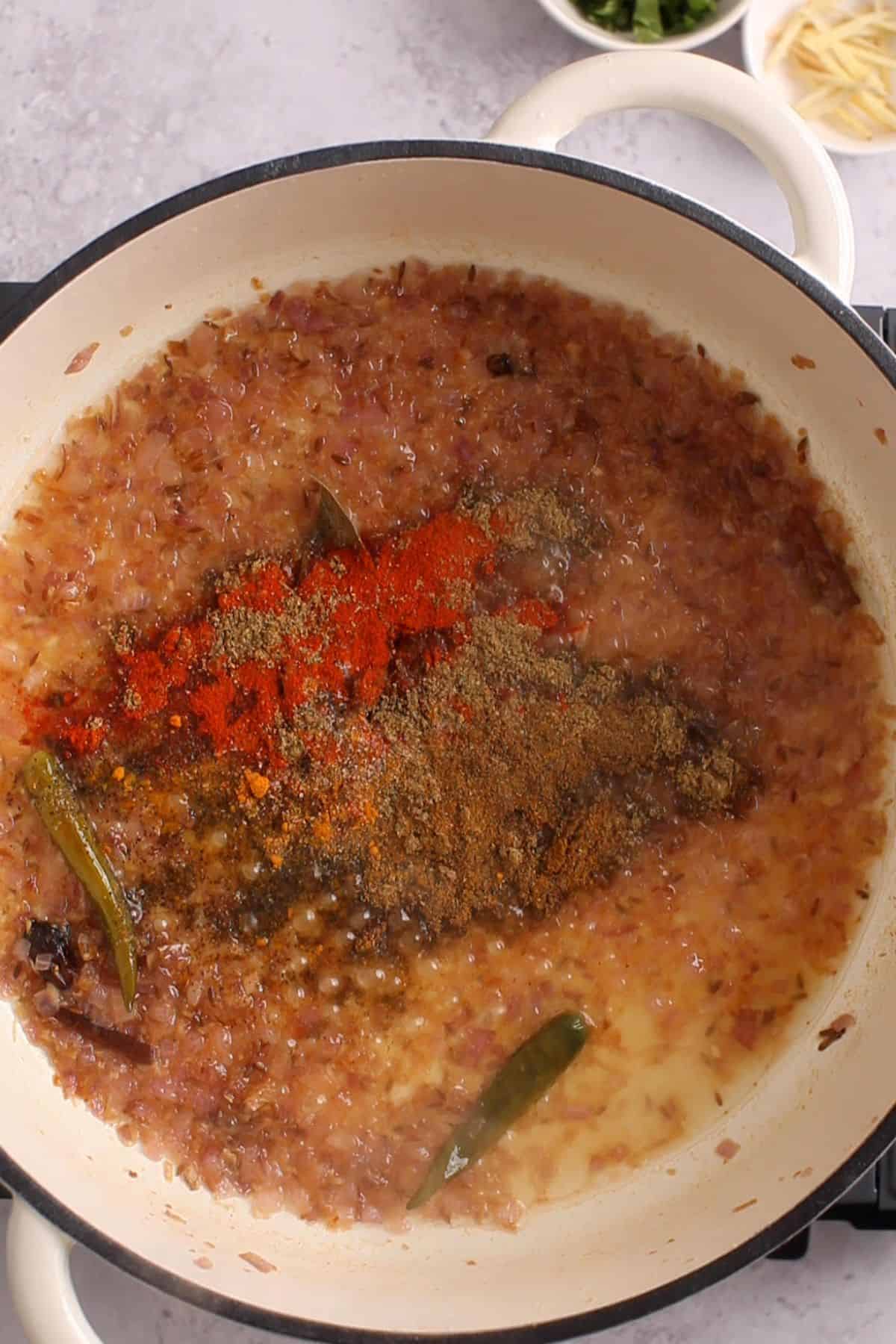 Ground spices are added to the cooking pot.