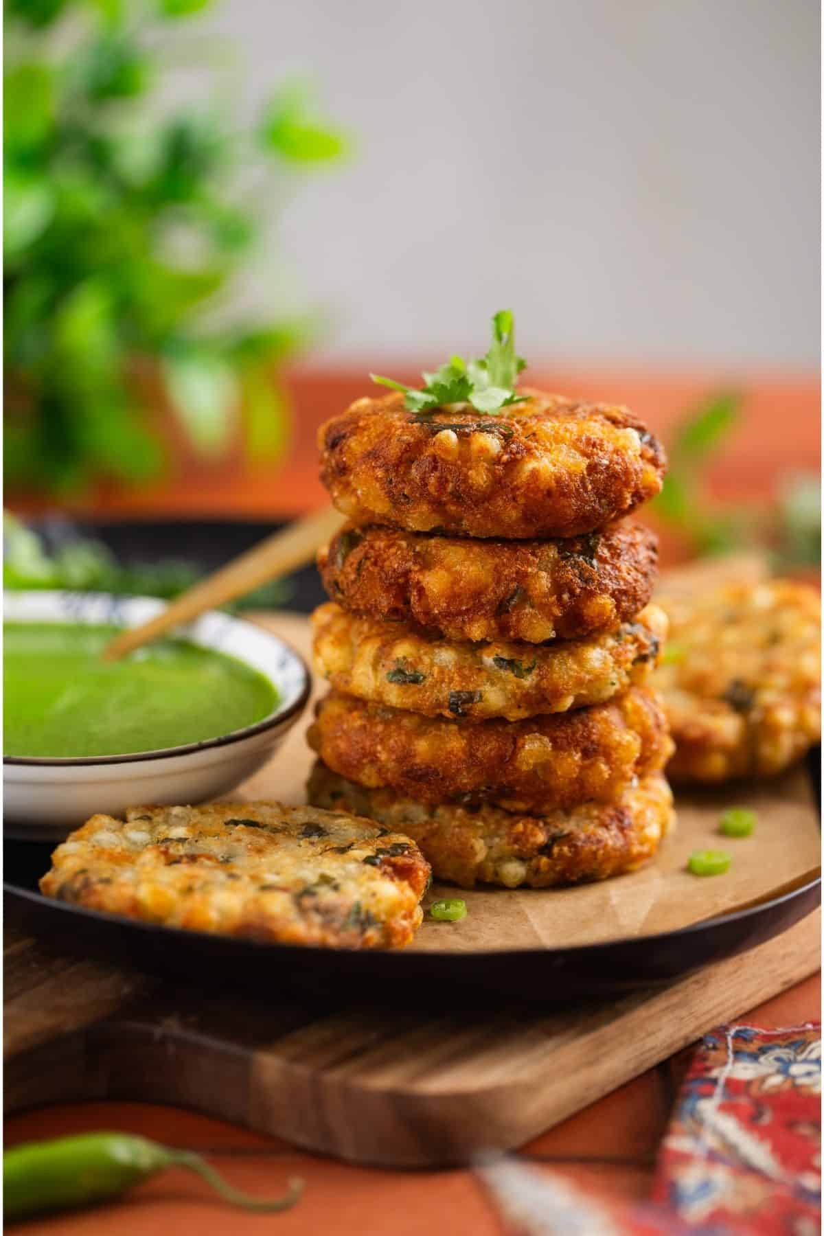 Sabudana Vada stacked one on top of other with green chutney on the side. 
