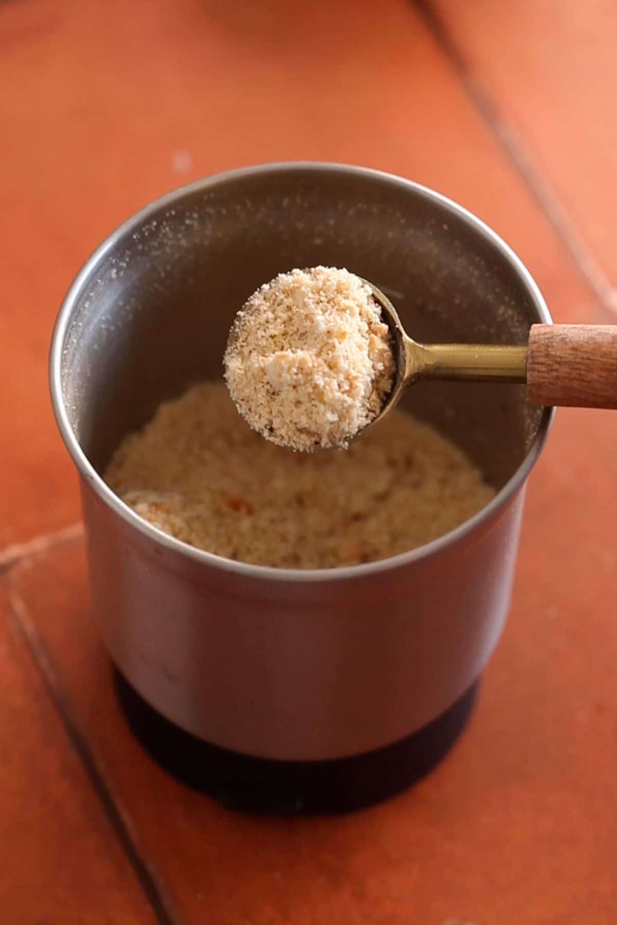 Peanuts are crushed in a small blender jar into a coarse powder.