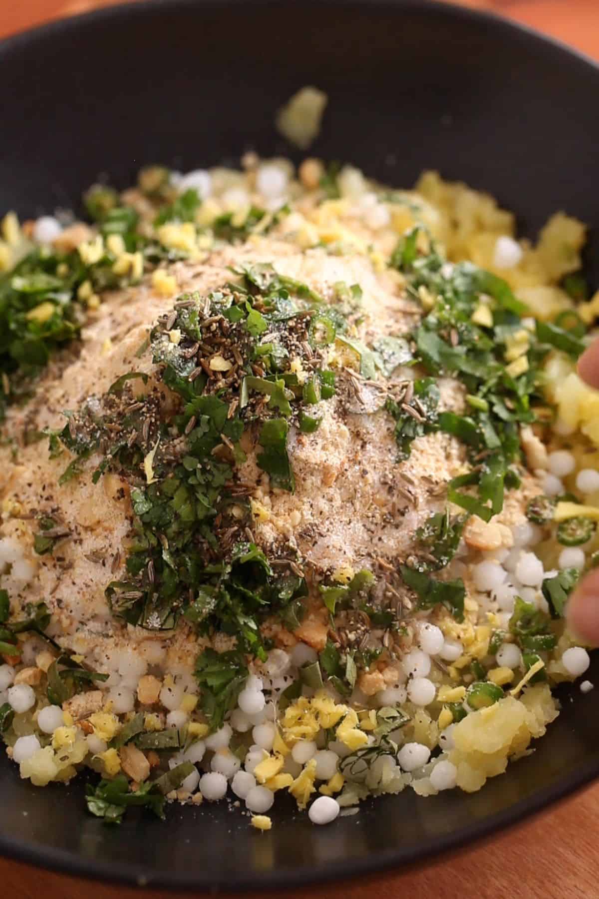 All the ingredients for making sago vada are placed in a large black bowl. 