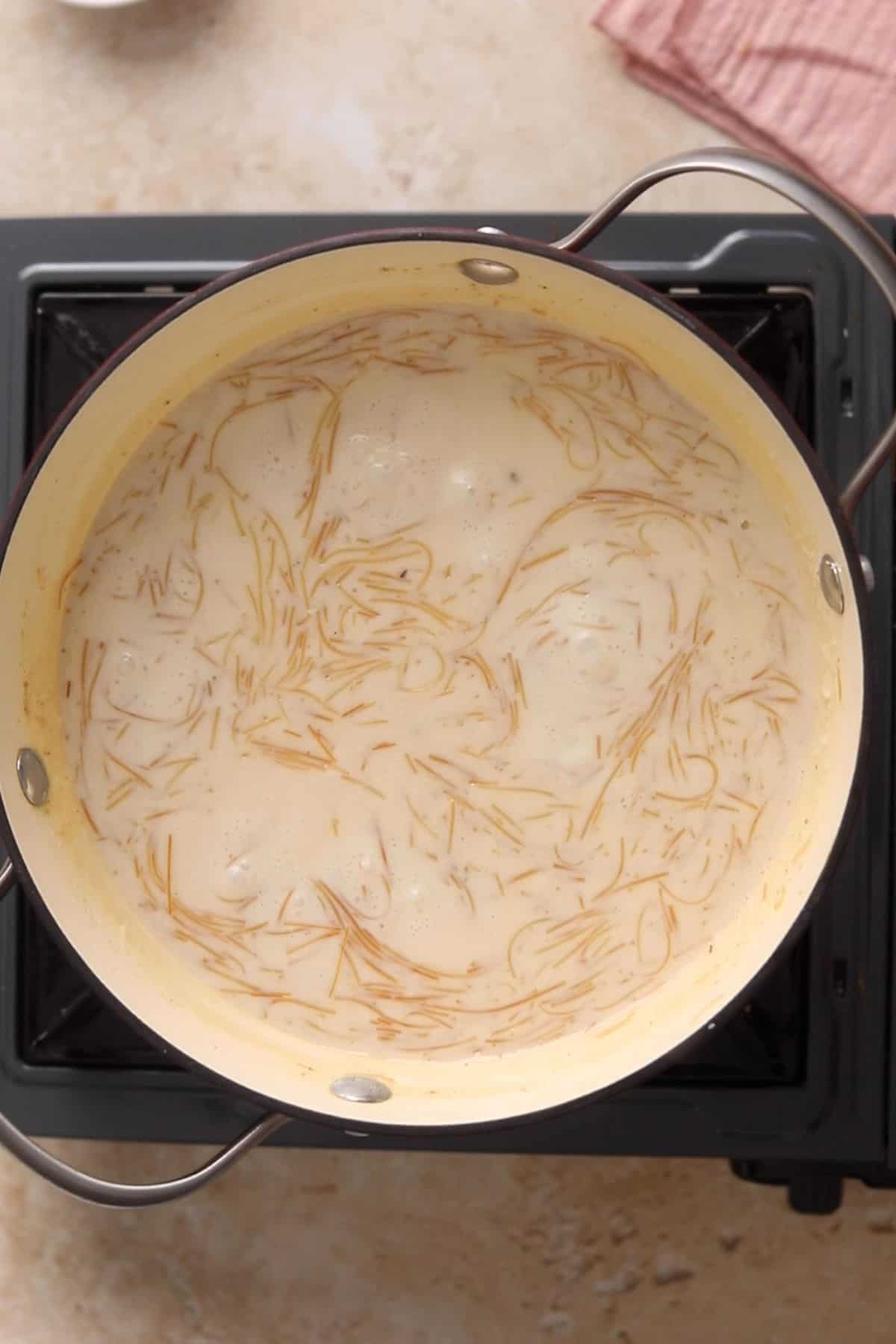 Sweet vermicelli kheer is seimmering and thickening on stove.