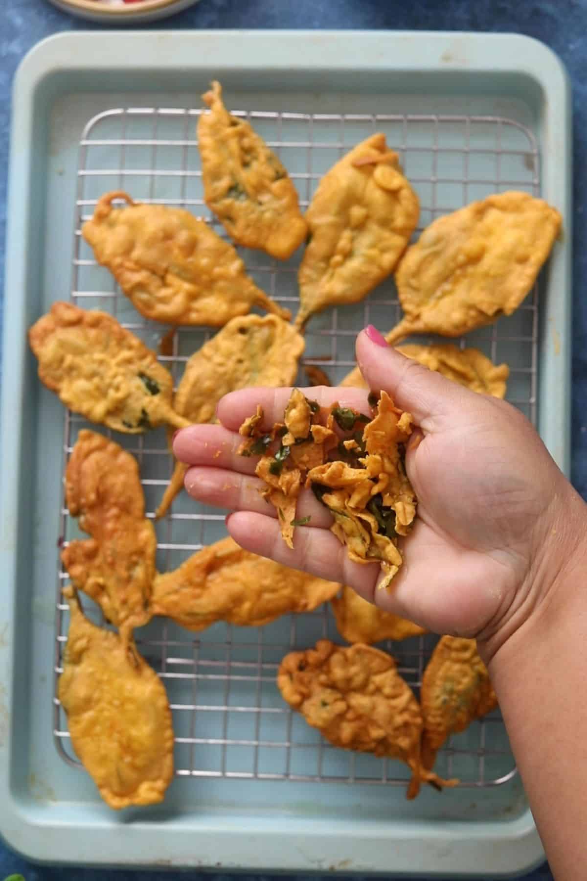A fried spinach leaf is crunched by hand to show its crispiness.