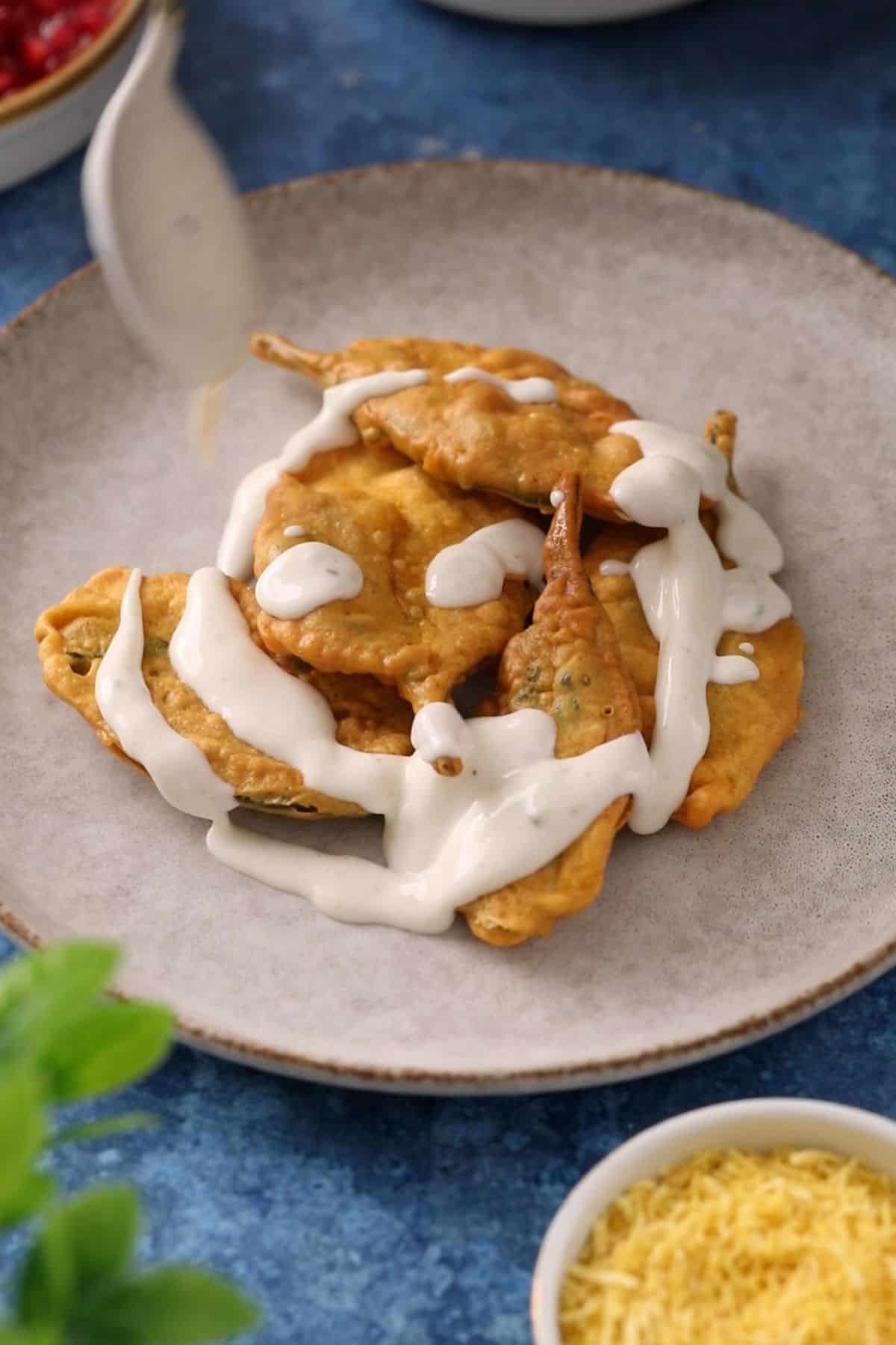 Yogurt is drizzled over fried spinach leaves.