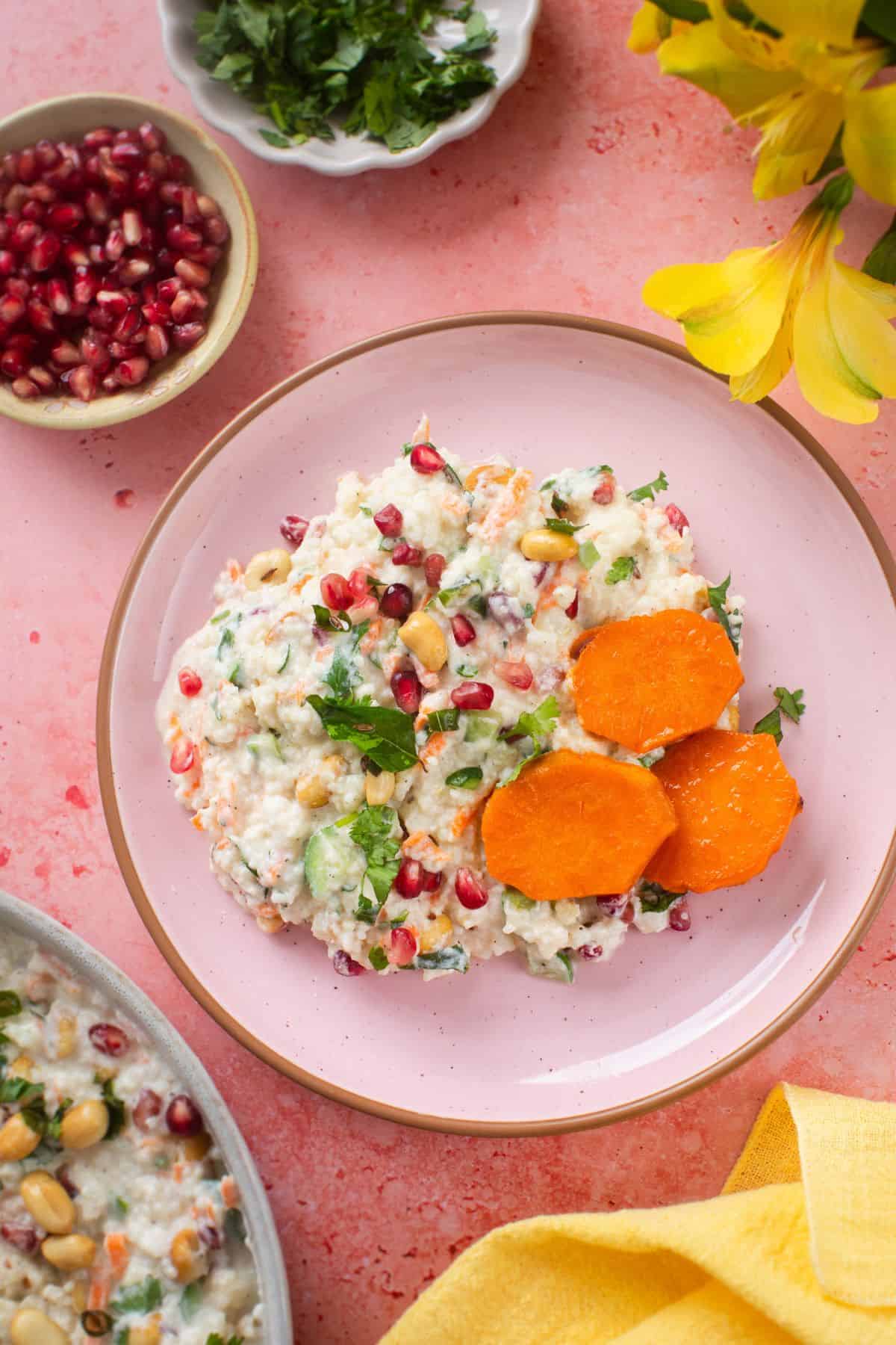 Top view of curd rice made with millets served in a pink plate with sweet potato slices.