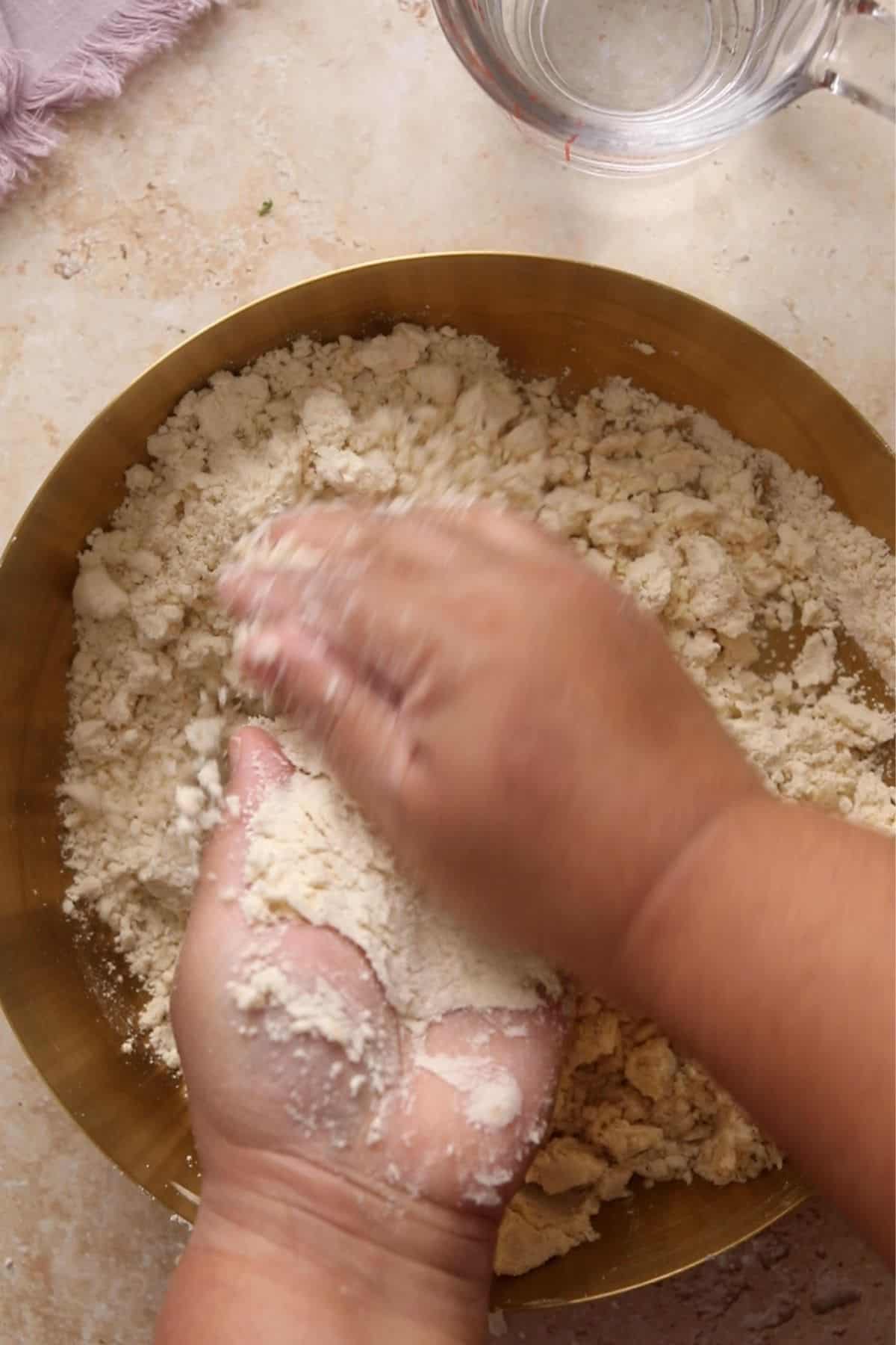 Ghee is rubbed in the flour using both hands. 