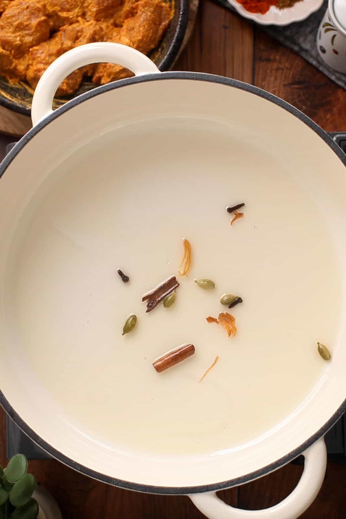 Whole spices are spluttering in oil.