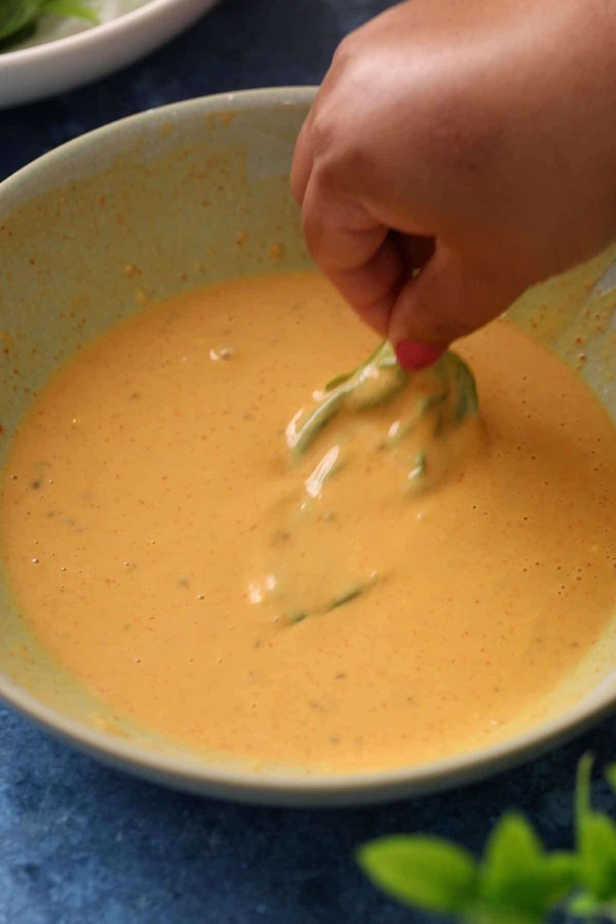 Spinach leaves are being coated in the besan batter.