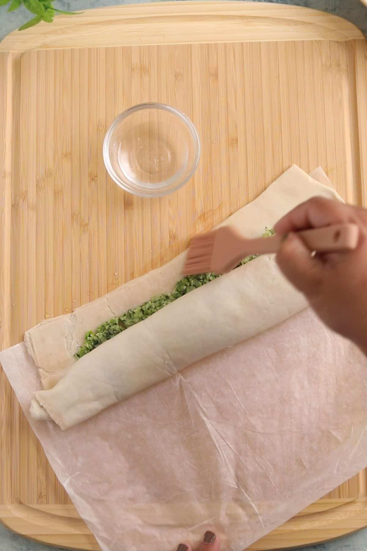 Water is added to seal the puff pastry roll.