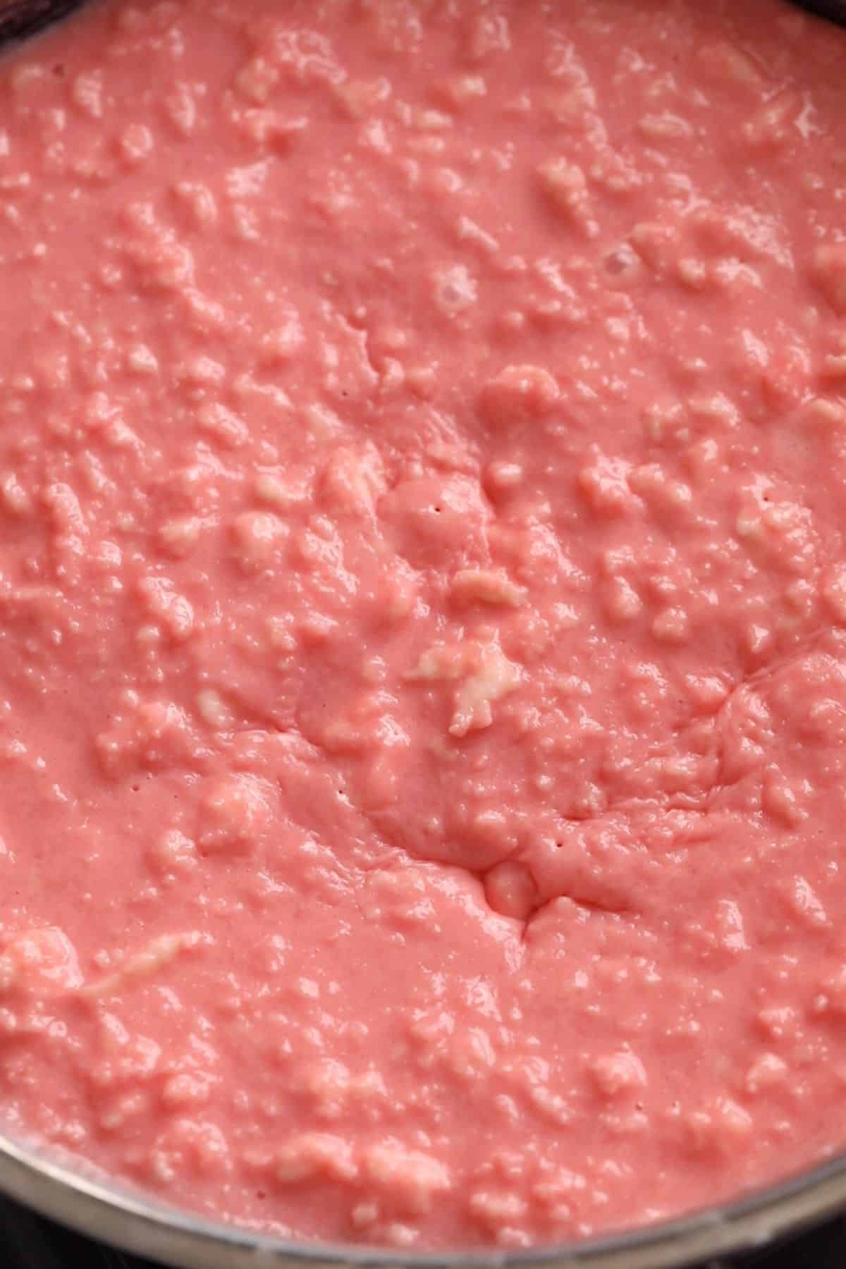 Paneer and rose milk mixture is slow cooking in a black pan.