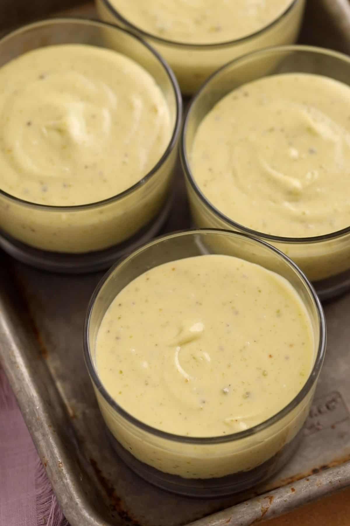 Pistachio ceesecake cups are placed in a tray to chill.
