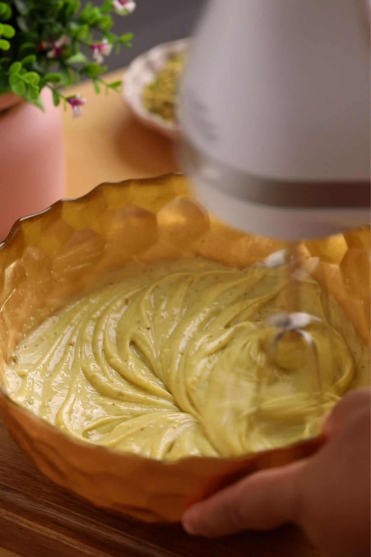 Cheesecake mixture is being beaten using a hand mixer. 