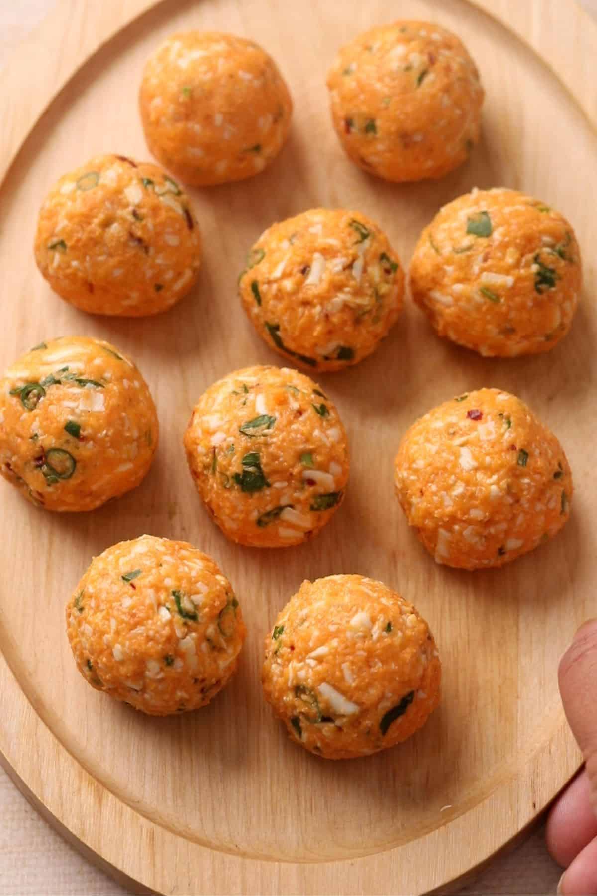 Shaped round sweet potato koftas are resting on an oval bamboo plate.