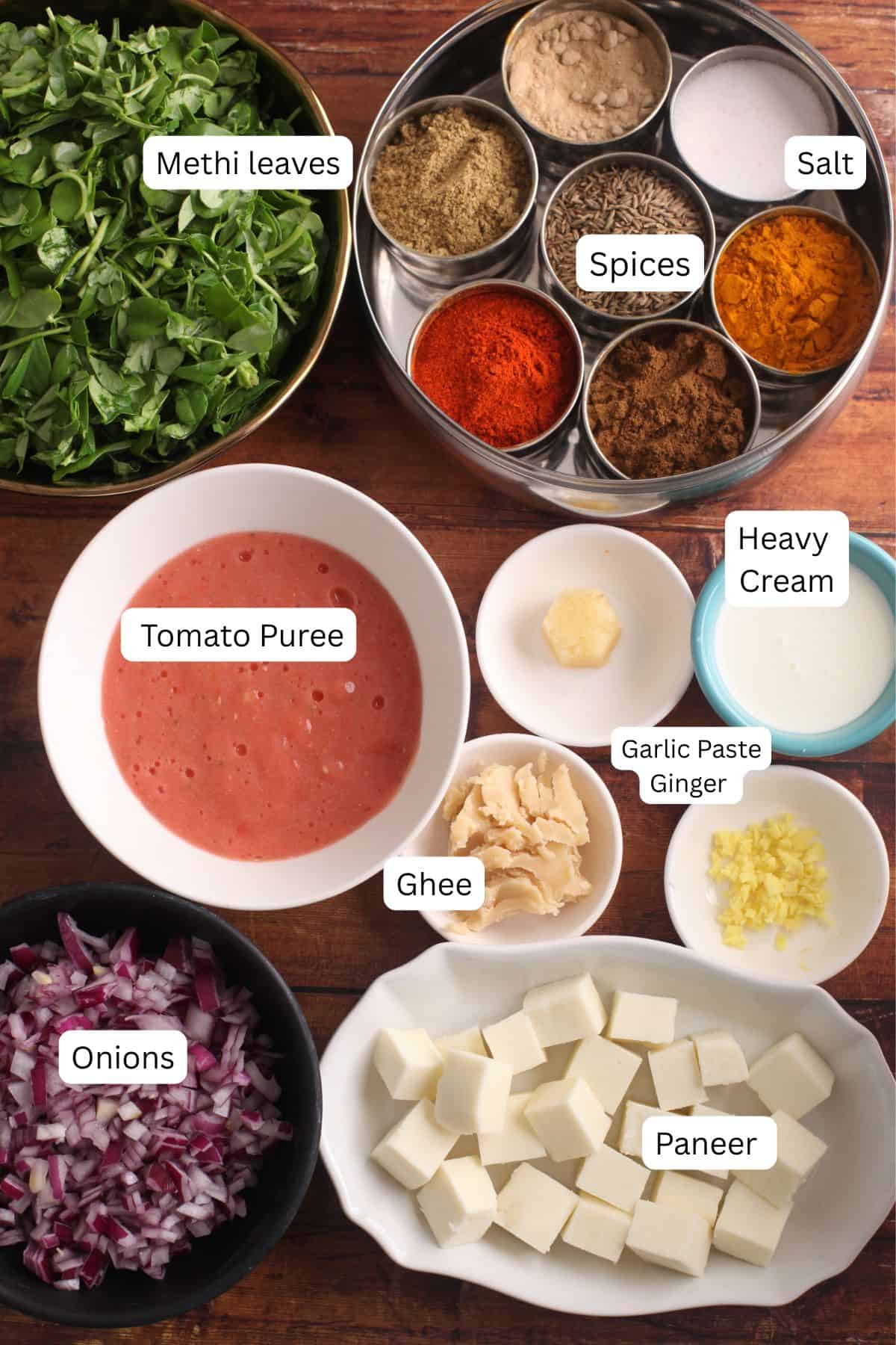 Ingredients needed to make dhaba methi paneer are placed on a wooden background.