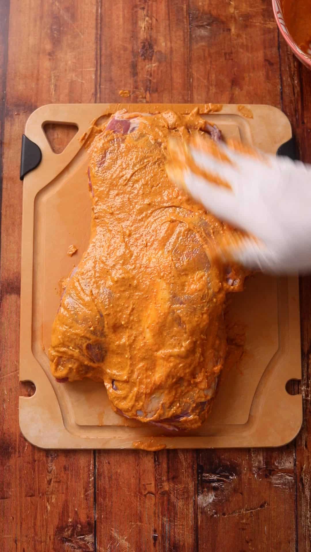 Marinade is spread on top side of the lamb leg.